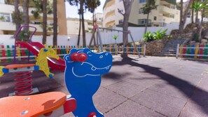 Un terrain de jeux doté d’équipements colorés, notamment un toboggan bleu en forme de crocodile et un toboggan jaune en forme de girafe.