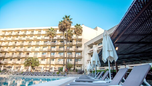 A hotel pool area with sun loungers and umbrellas, a large building with balconies, and palm trees. - BLUESEA Al Andalus (Torremolinos)
