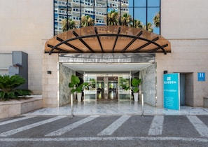 A hotel entrance with a modern design, featuring a glass door entrance, a covered waiting area, and a sign indicating the hotel name and location. - BLUESEA Al Andalus (Torremolinos)