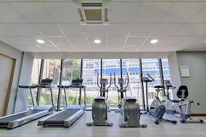 Une salle de sport équipée de tapis de course, d’appareils elliptiques et de vélos d’appartement.