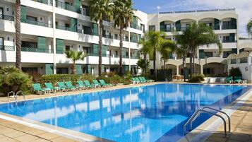 Alberca al aire libre, sombrillas en la alberca y camastros