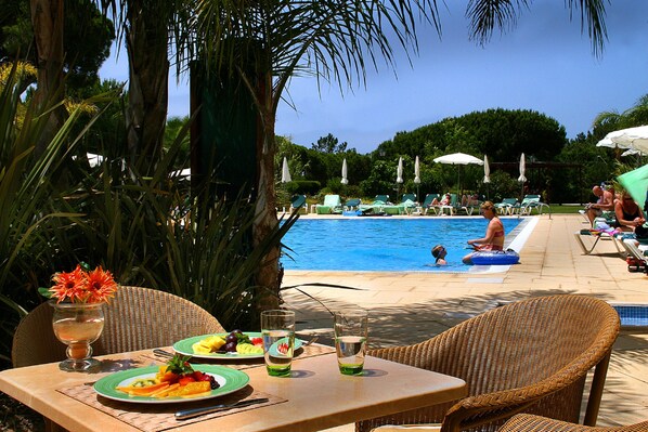 Una piscina al aire libre, sombrillas, sillones reclinables de piscina