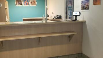 A reception area with a counter, a phone, a computer, and a wall with numbered pictures.