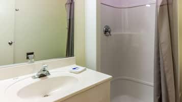 A bathroom with a white sink, a mirror, and a shower with a curtain.