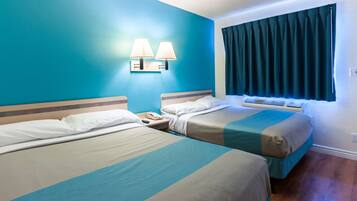 A hotel room with two beds, a nightstand with a phone, and a window with curtains.