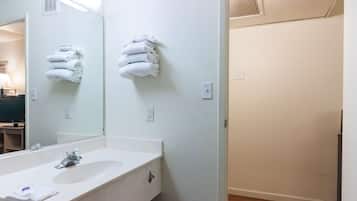 A bathroom with a white sink, a mirror, and two towel racks on the wall.