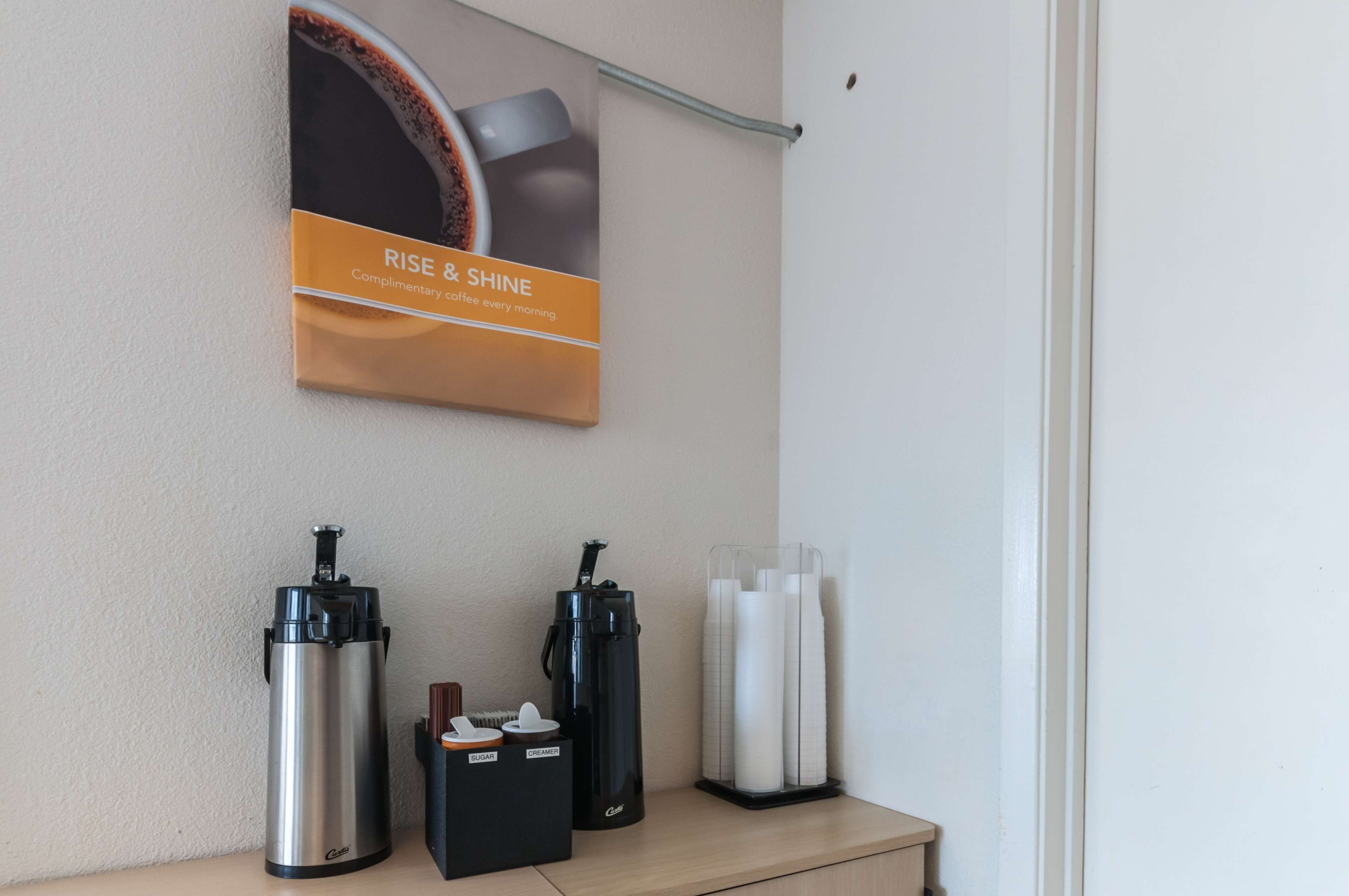 A coffee station with a coffee maker, a thermos, and a coffee dispenser on a counter.