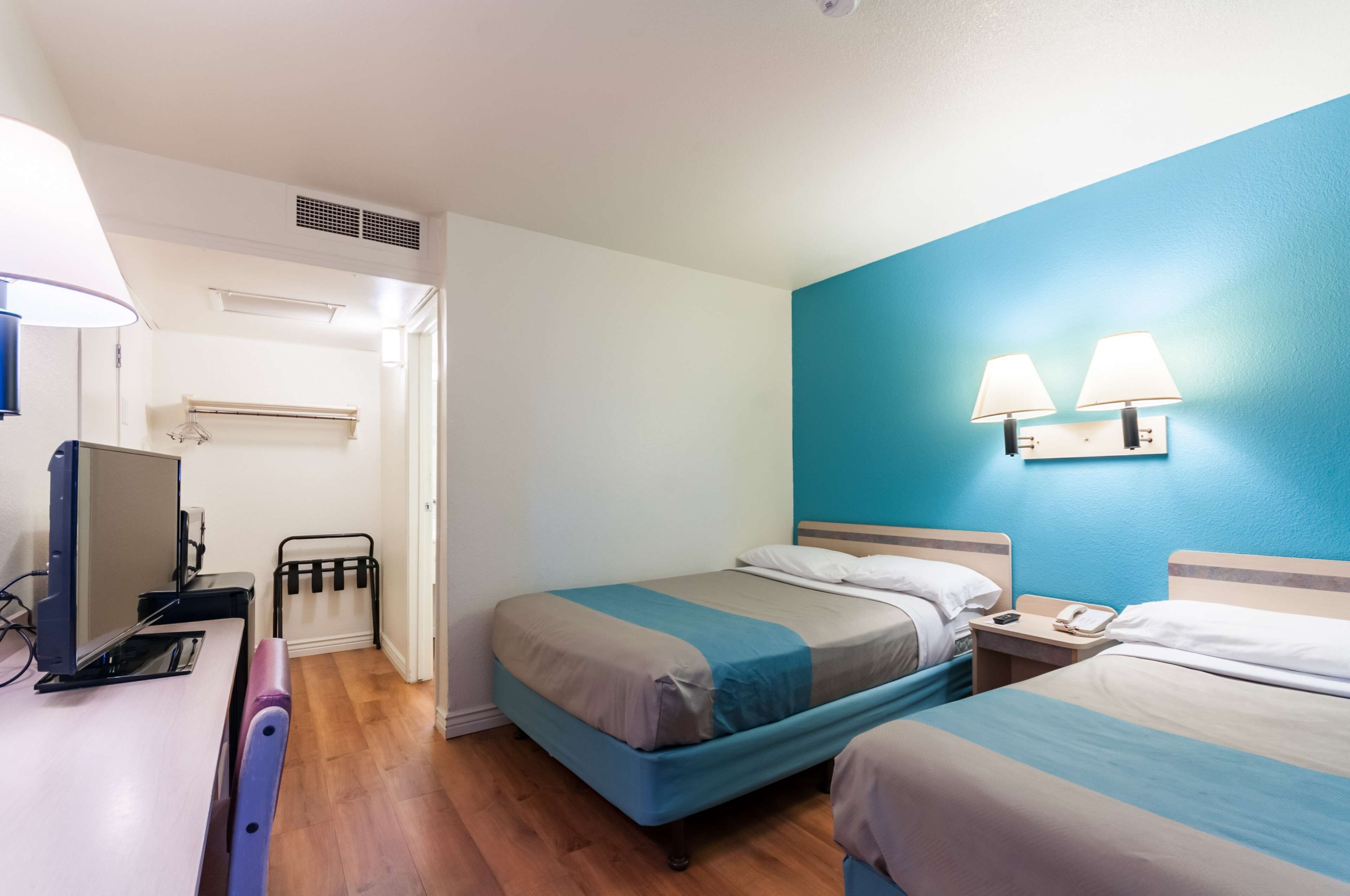 Een hotelkamer met twee bedden, een bureau met een computer, een bureaulamp en een wandradiator.