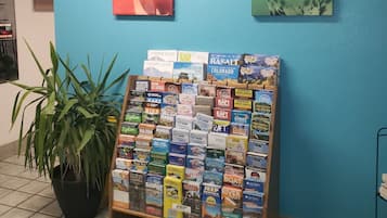 Un kiosque d’information touristique où sont exposés des guides de voyage et où se trouve une plante en pot.