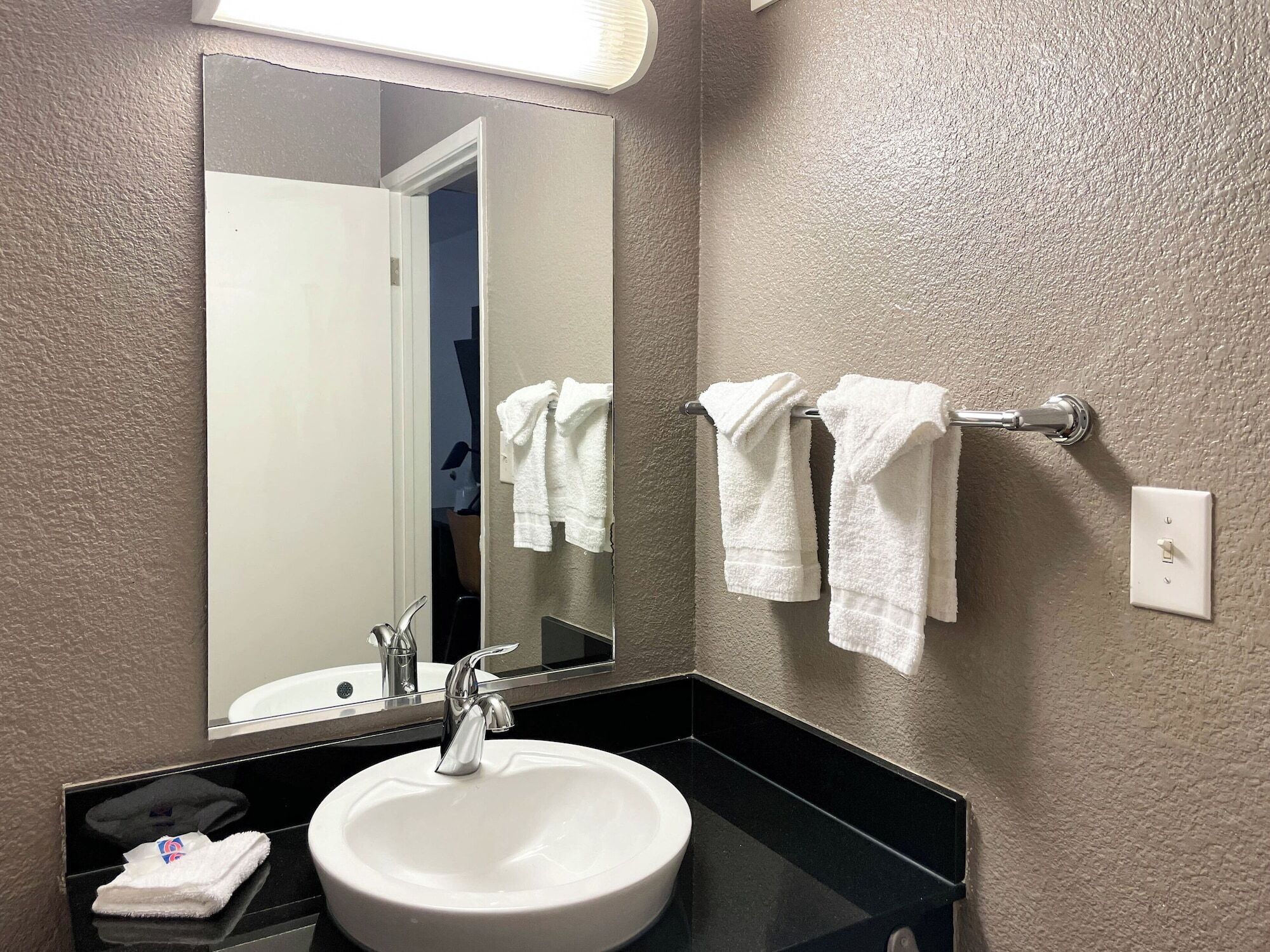 A bathroom with a white sink, a mirror, and two towels hanging on a towel rack.