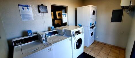 A laundry area with a front-loading washer and dryer, a digital scale, and a paper towel dispenser.