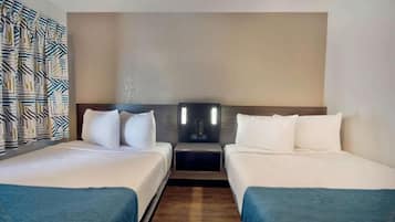 Habitación de hotel con dos camas, cabecera con iluminación integrada y cortina estampada.