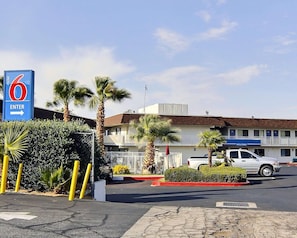 Et motel med tydelig skilt, palmer og en hvid pickup-truck foran.