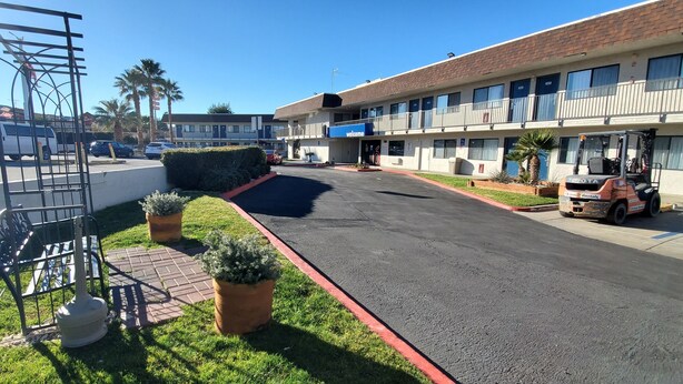 Un parking avec un chemin piétonnier dallé, un fourgon blanc et un bâtiment sur lequel on peut lire l’inscription « Bienvenue ».