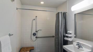 A bathroom with a shower, a toilet, a sink, and a towel rack.