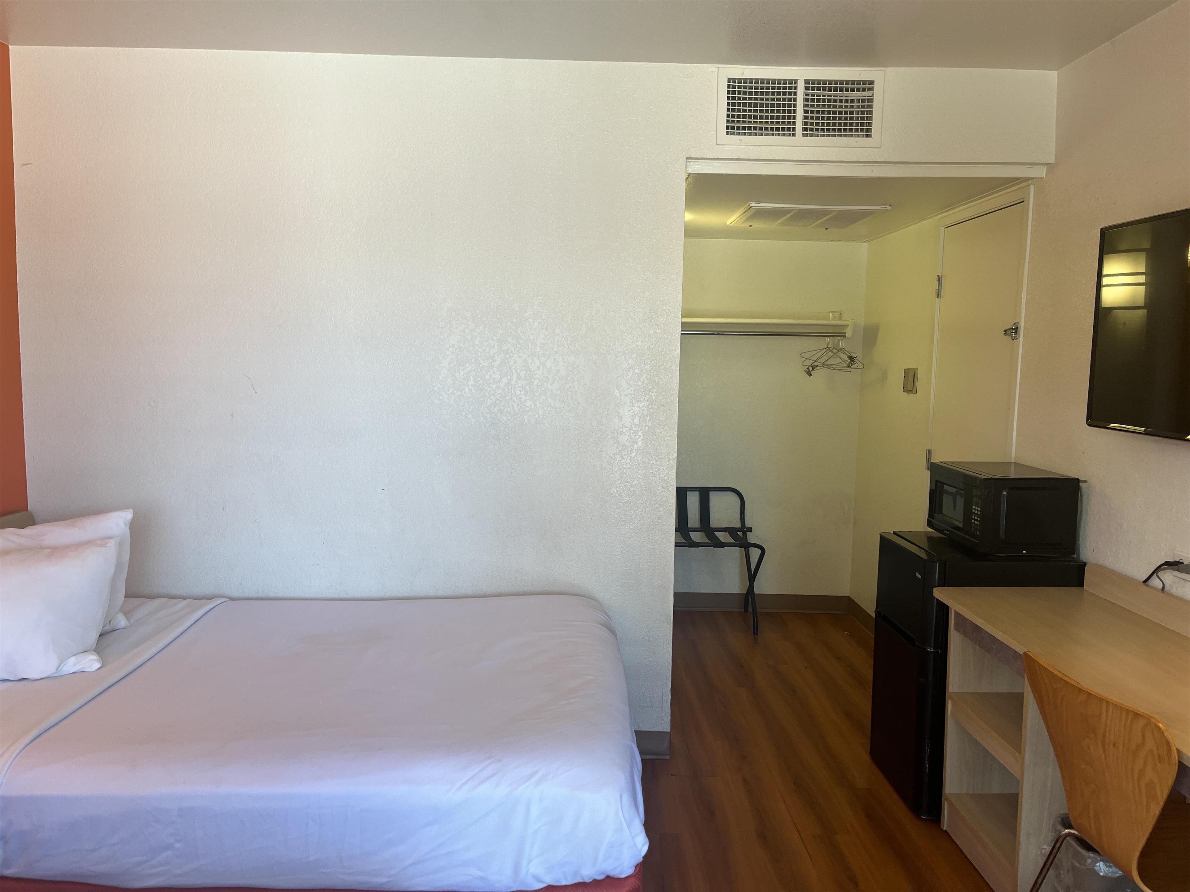 A hotel room with a bed, a desk, a microwave, and a wardrobe.