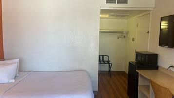 A hotel room with a bed, a desk, a microwave, and a wardrobe.