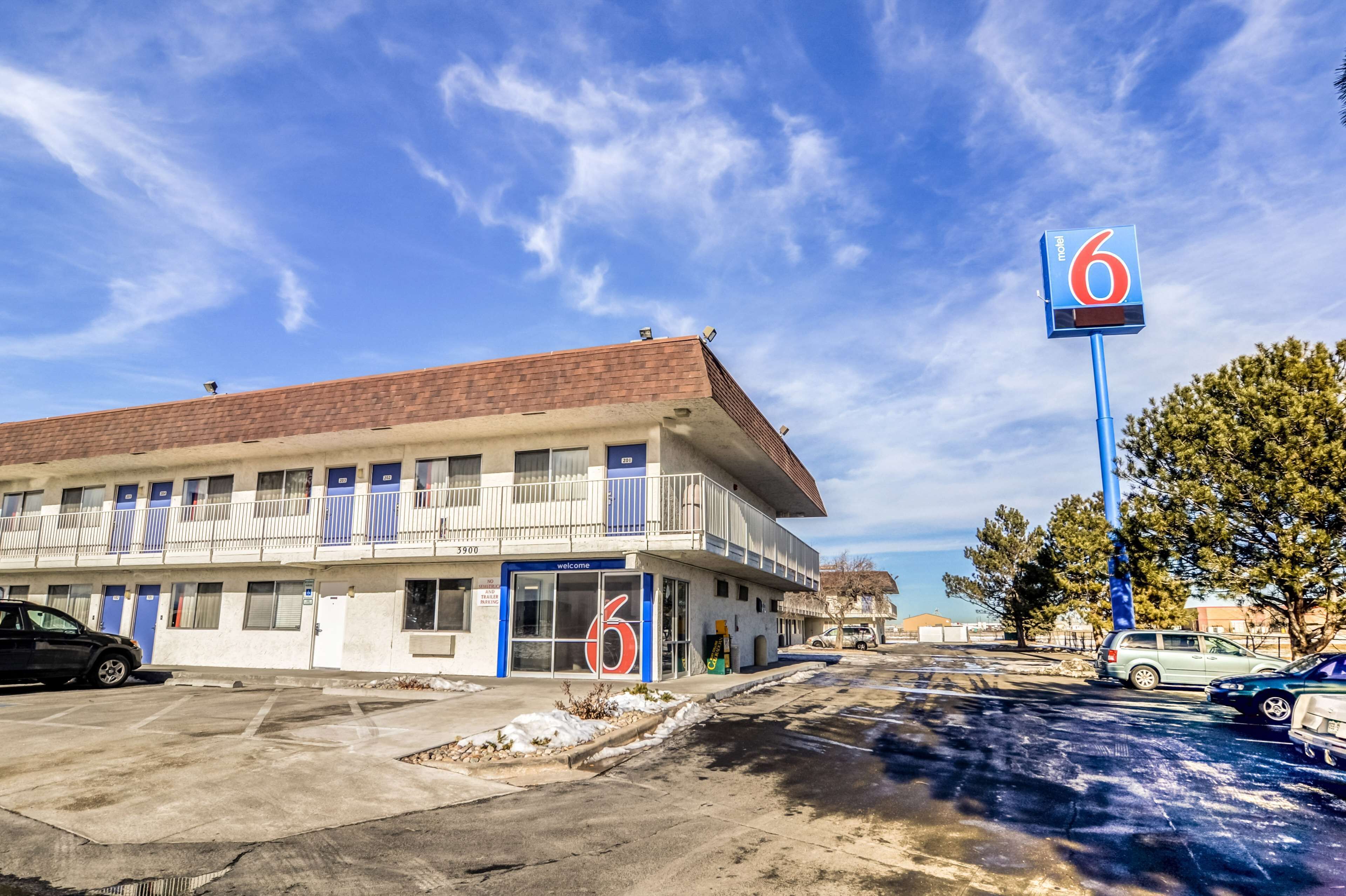 Un motel avec une enseigne indiquant le chiffre « 6 », un parking et un ciel d’un bleu limpide.