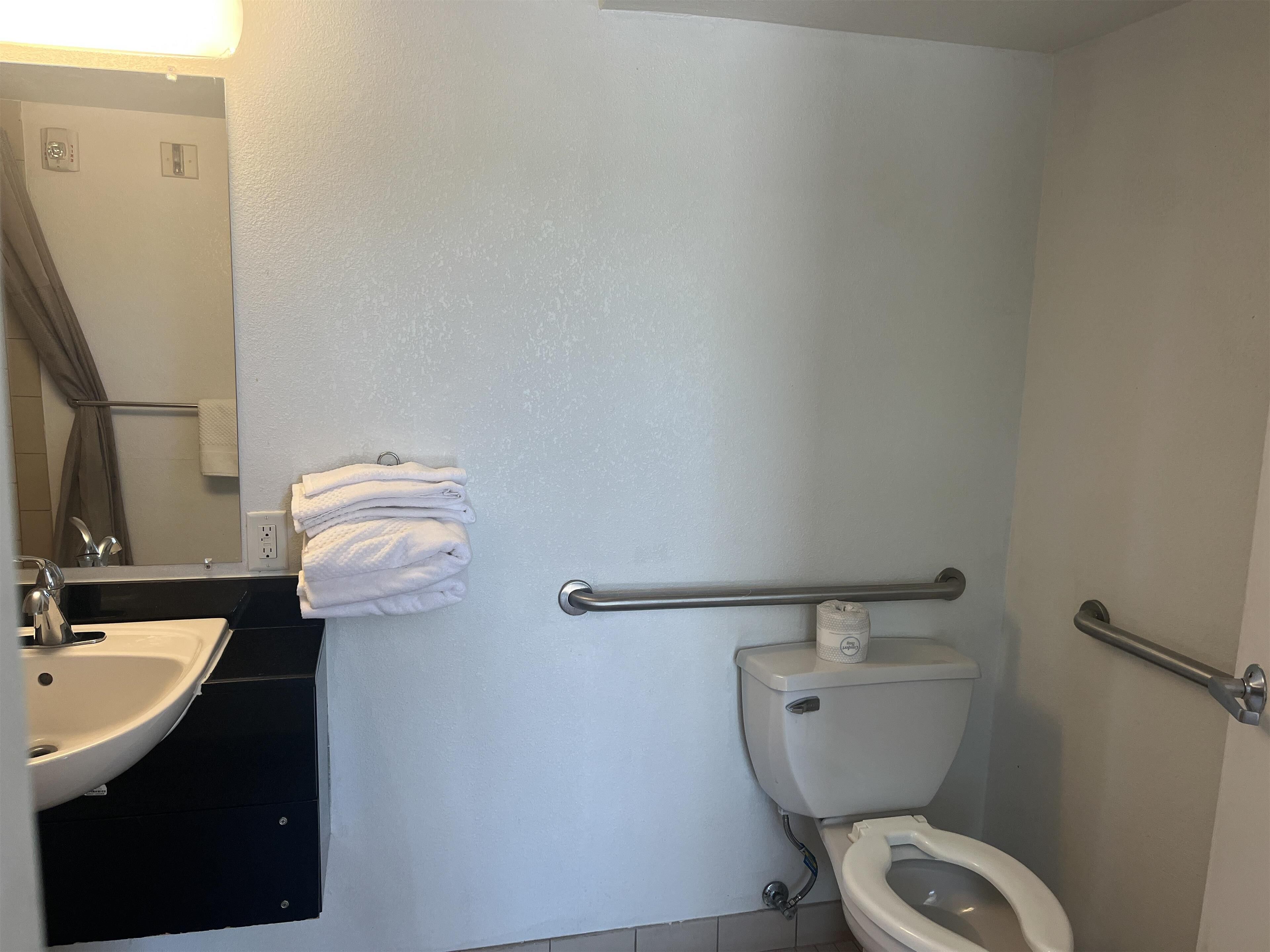 Un baño con lavamanos, inodoro y toallero.