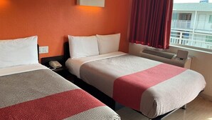 A hotel room with two beds, a window with a view, and a red curtain.