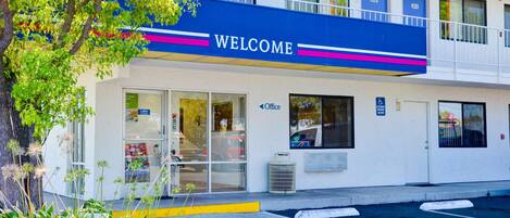 A building with a 'WELCOME' sign, an office sign, and a handicap parking sign.