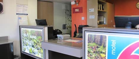 Un área de recepción con mostrador, televisor y un letrero que indica un motel.