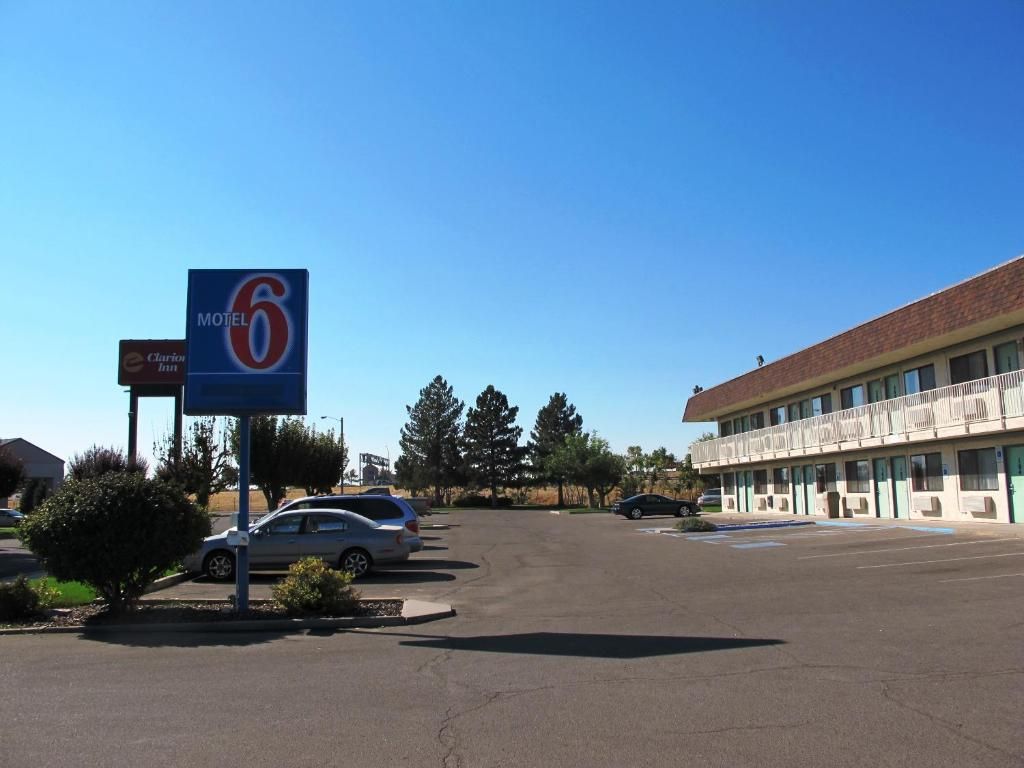 A motel with a prominent sign, a parking lot, and a building with a balcony.