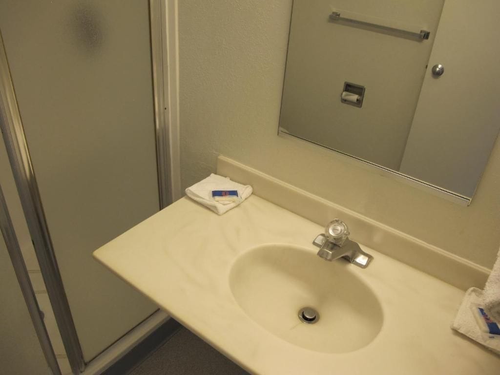 Un baño con lavamanos, espejo y un perchero para toallas.