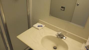 Un baño con lavamanos, espejo y un perchero para toallas.