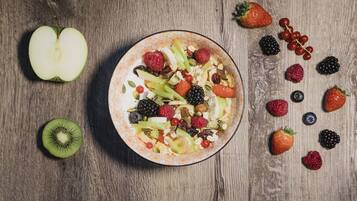 Un tazón de ensalada de frutas con diversas bayas y nueces sobre una mesa de madera.