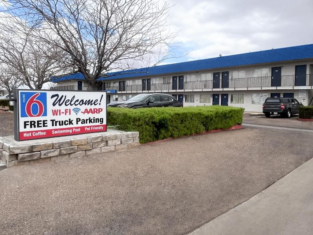 Un motel con un letrero que indica estacionamiento gratuito para camiones, Wi-Fi, beneficios para socios de AARP y servicios para mascotas.