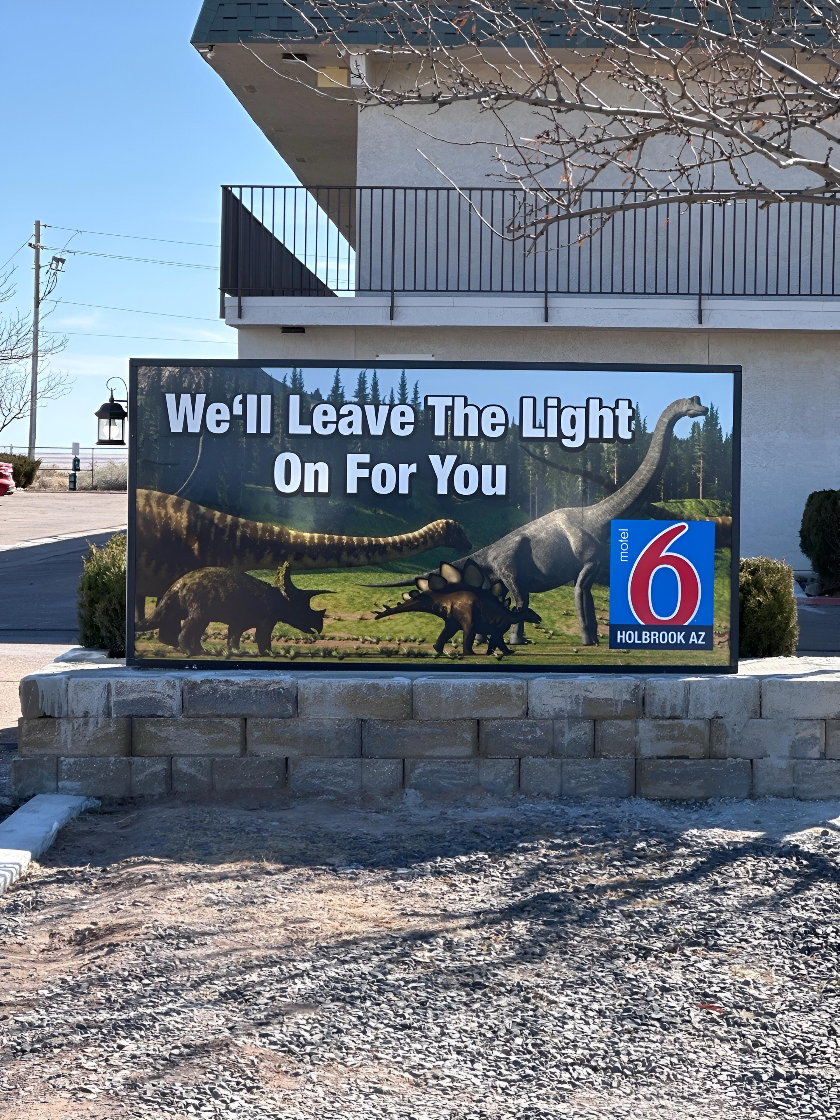 A billboard advertising a motel with a dinosaur theme, located in Holbrook, AZ.