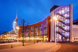 A modern hotel with a curved facade, multiple floors, and a prominent staircase. - Holiday Inn Express Portsmouth - Gunwharf Quays by IHG (Portsmouth)