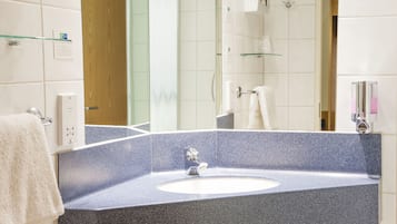 Un baño con lavamanos de encimera de granito, un espejo y cabina de ducha con paredes de vidrio.