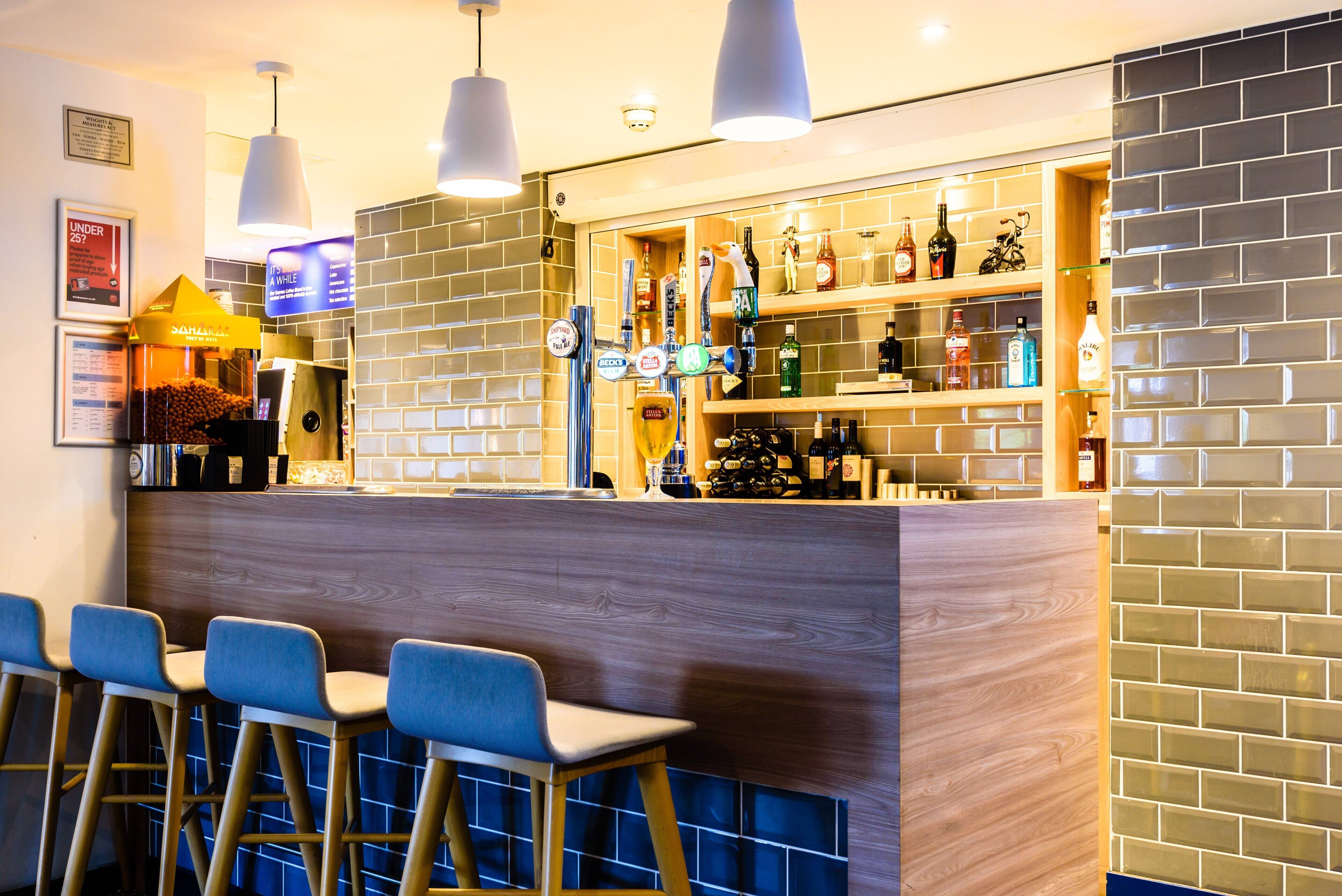 Een bar met krukken, een toonbank en gevulde flessenkasten.