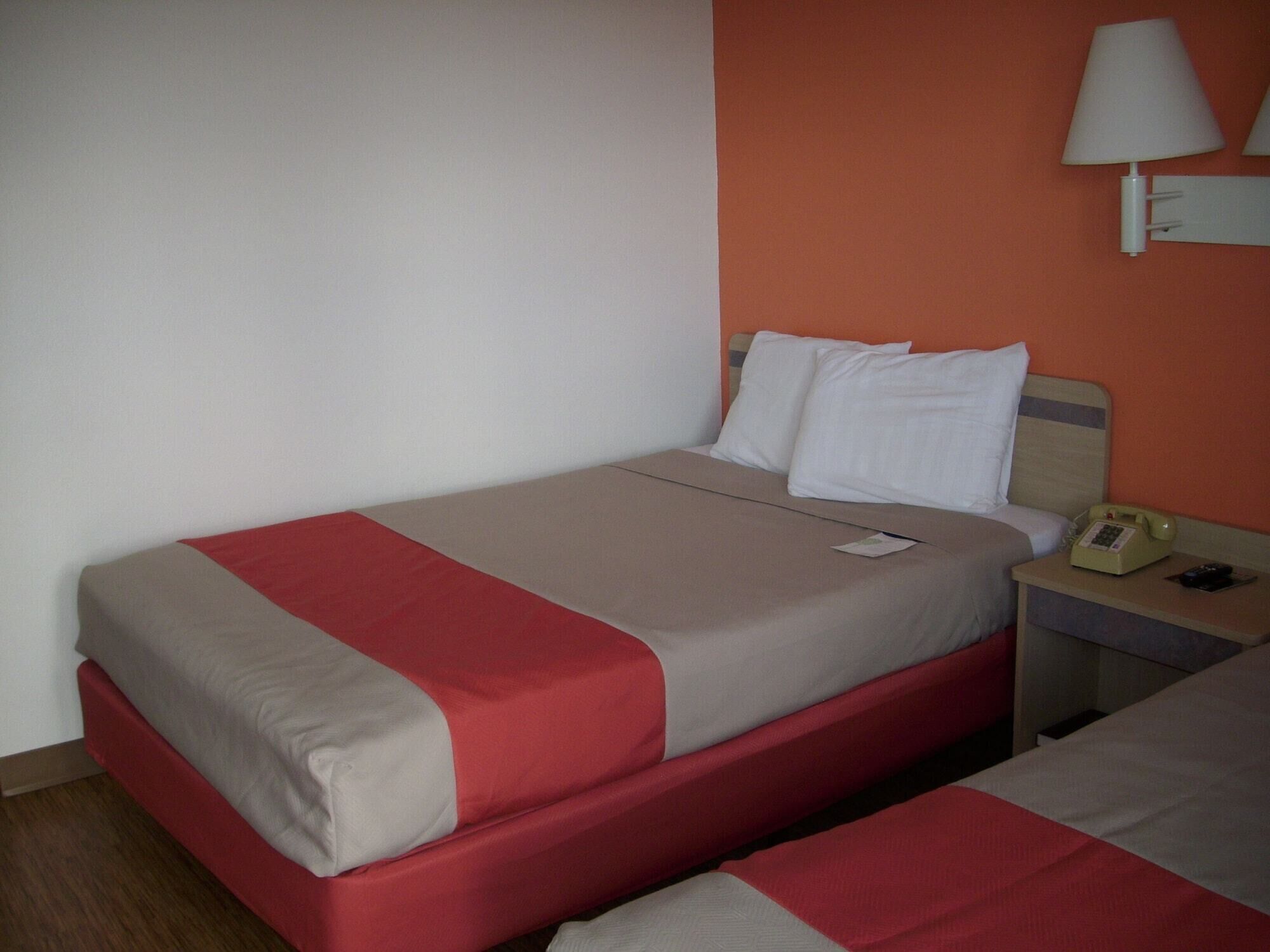 A hotel room with a bed, a nightstand, a lamp, and a telephone.