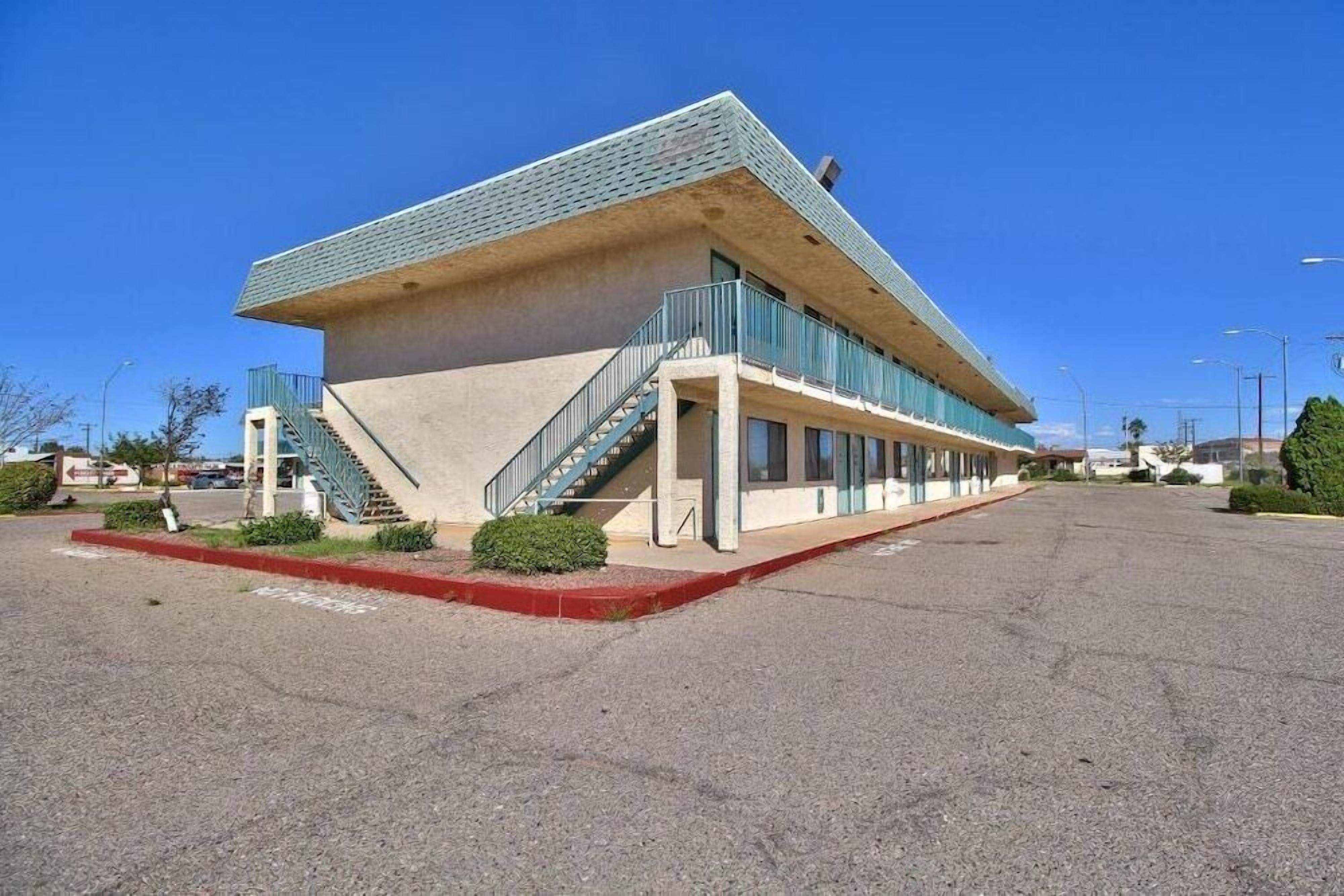 A modern building with a flat roof, a staircase leading to the entrance, and a parking lot in front.