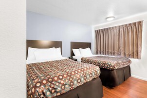 Quarto de hotel com duas camas, cada uma com colcha estampada e cabeceiras combinando.