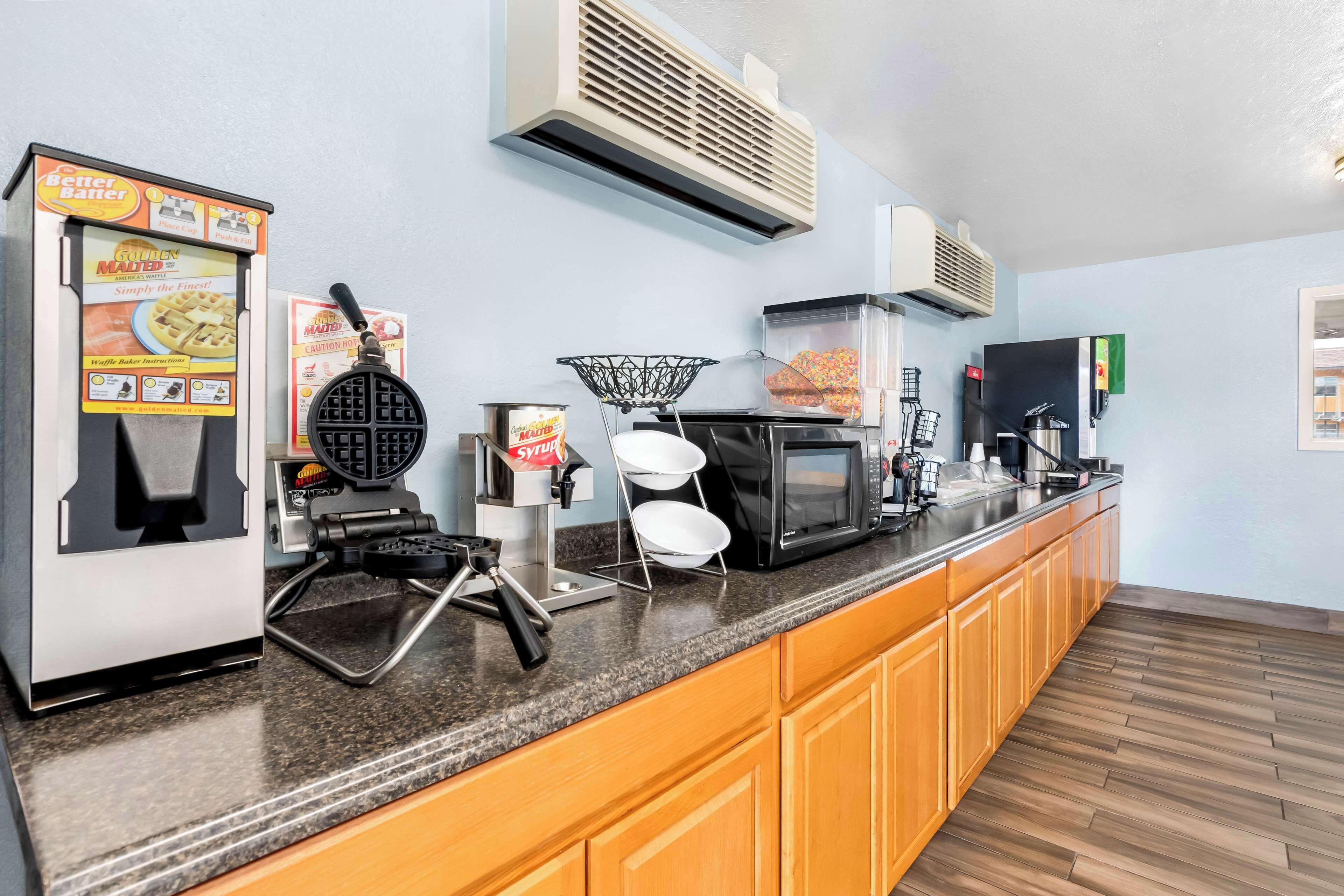 A kitchenette with a waffle maker, a coffee machine, and a microwave.