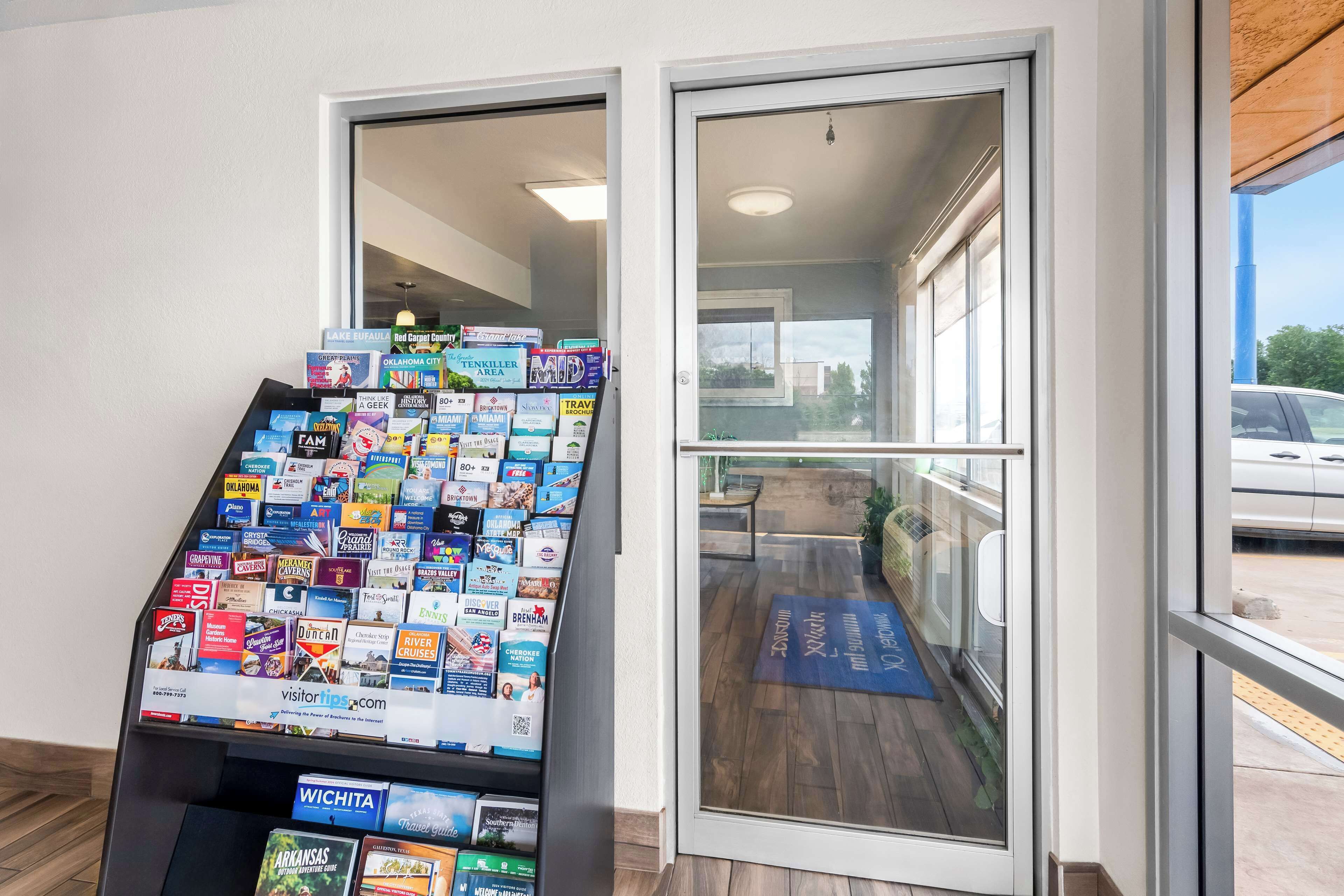 A display of travel brochures in a hotel lobby with a view of the outside through the glass doors.
