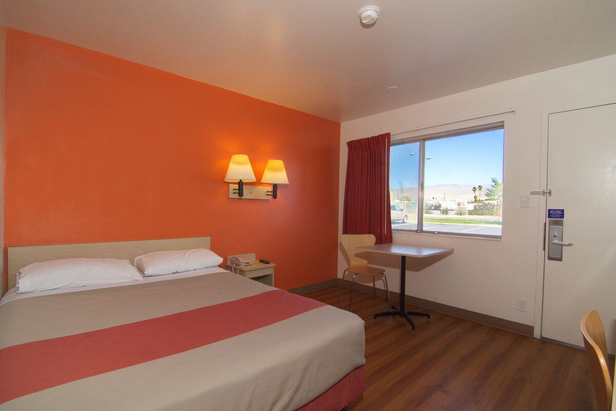 A hotel room with a bed, a desk, a chair, and a window with a view.