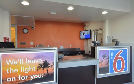 A motel reception desk with a sign that reads "We'll leave the light on for you."