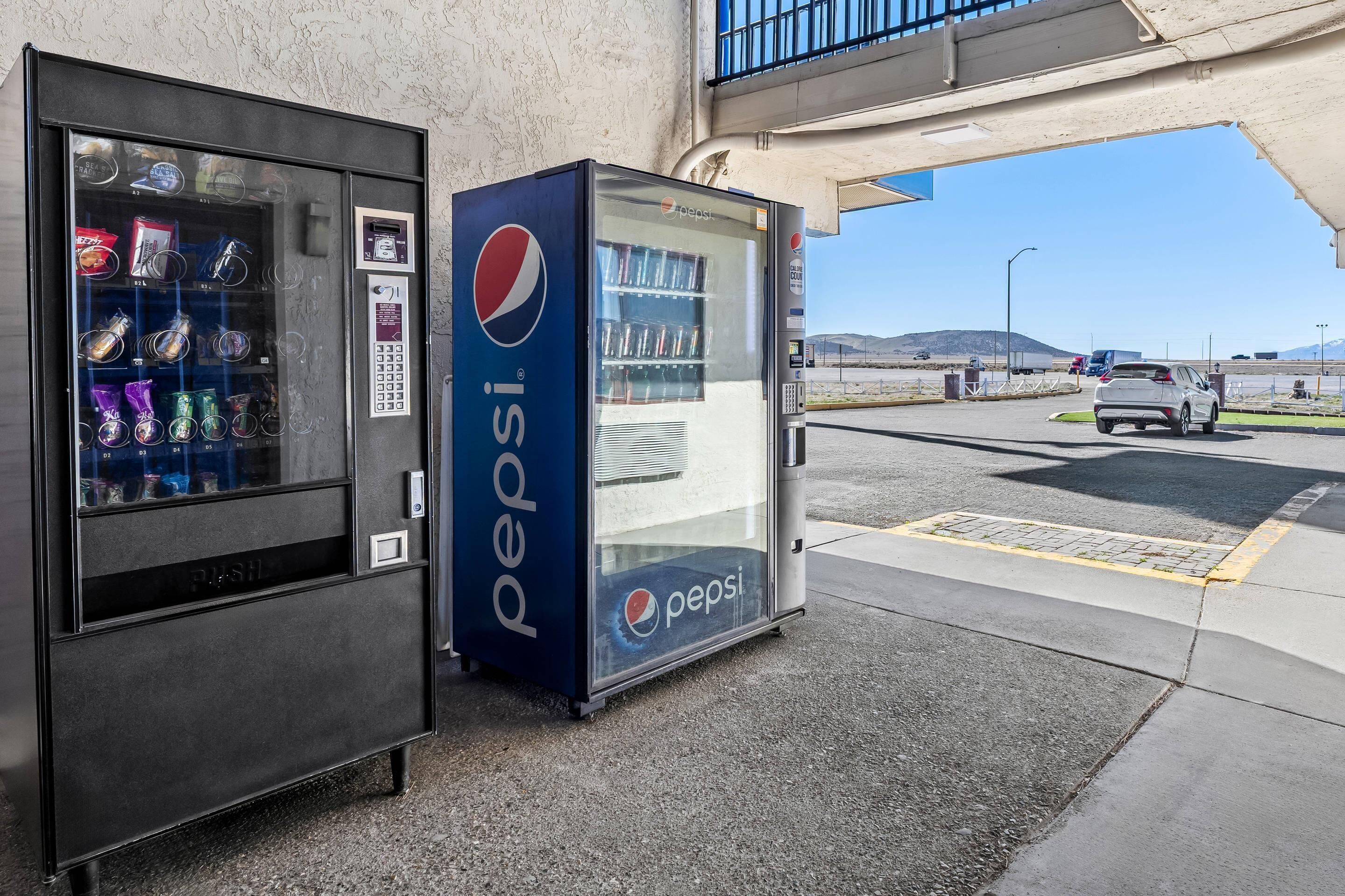 Una máquina expendedora y un refrigerador de Pepsi en un lugar a la carretera.