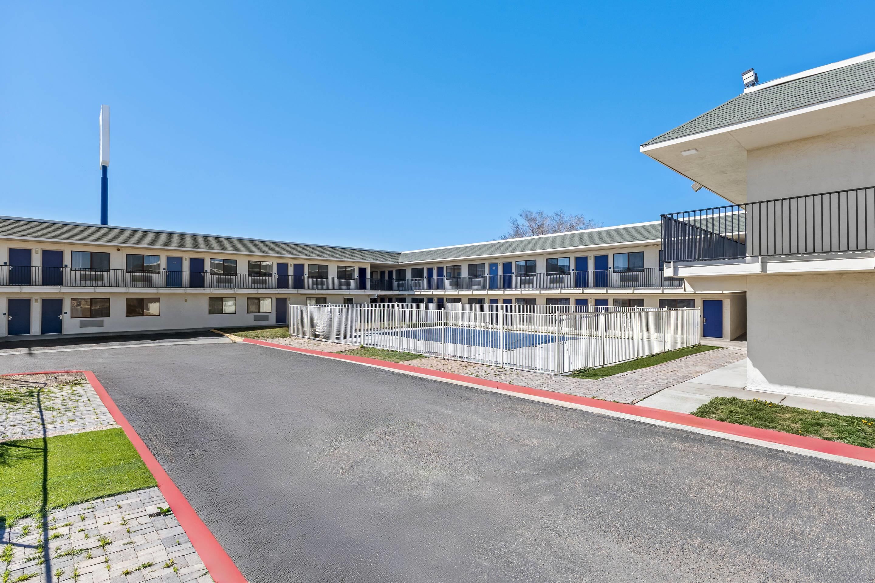A hotel with a pool, a parking lot, and a building with multiple windows and doors.