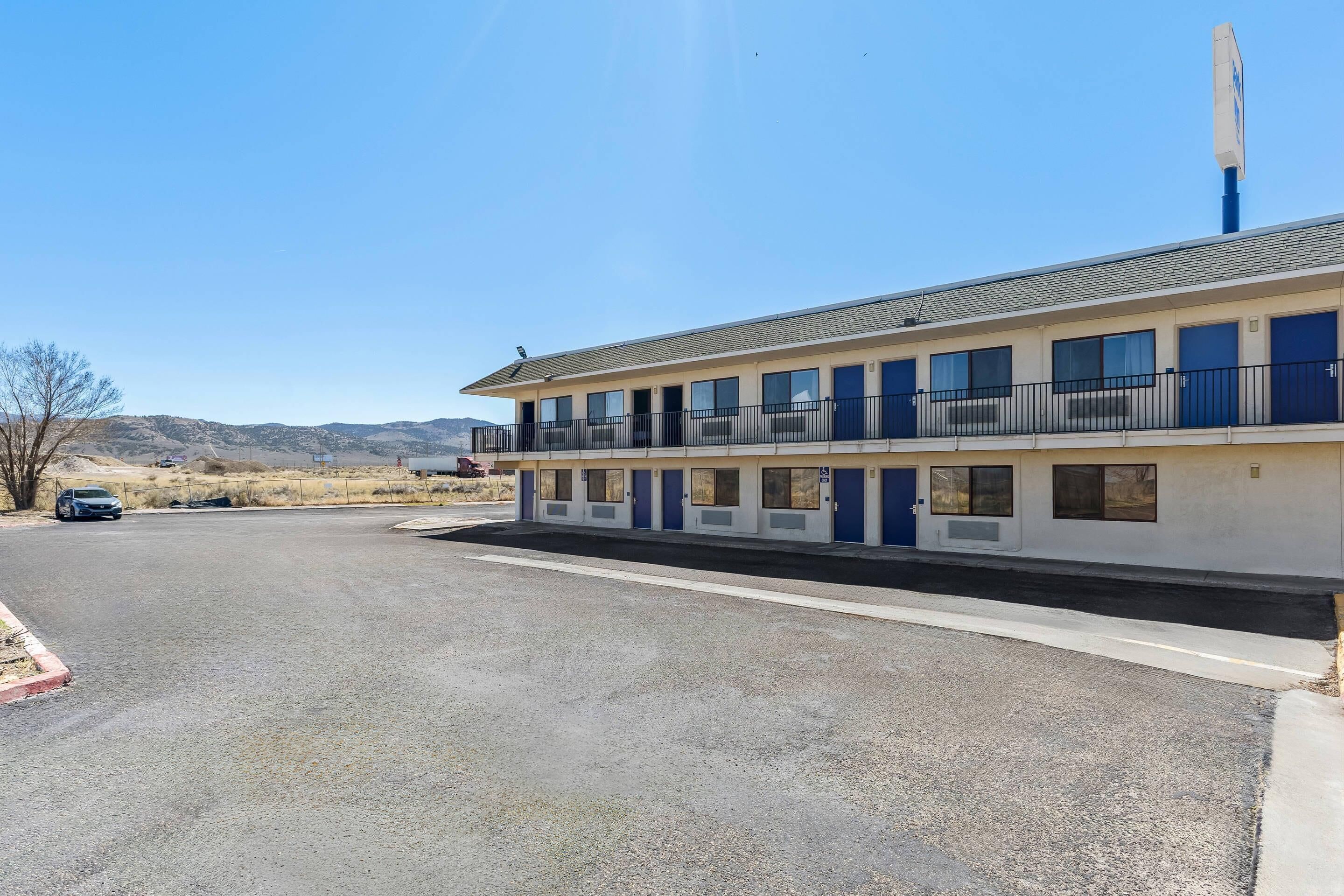 A motel with a flat roof, multiple windows, and a parking lot.