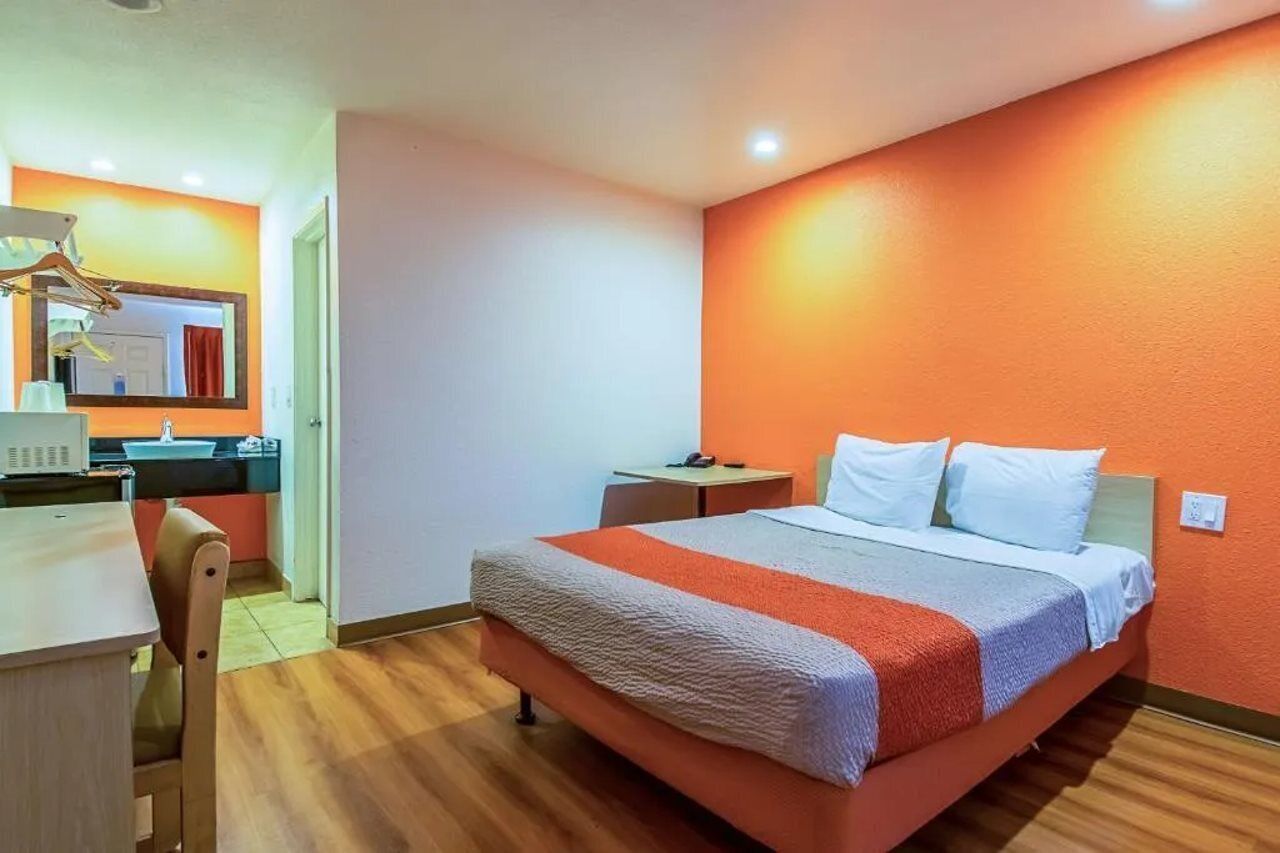 Ein Hotelzimmer mit Bett, Schreibtisch, Stuhl, Spiegel und einem kleinen Tisch.