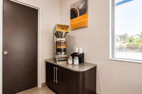 A coffee machine on a counter with a window view, a door, and a wall-mounted sign.