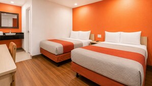 Een hotelkamer met twee bedden, een tafeltje, een stoel, een wastafel en een spiegel.