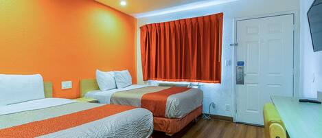 Habitación de hotel con dos camas, un escritorio y una televisión.