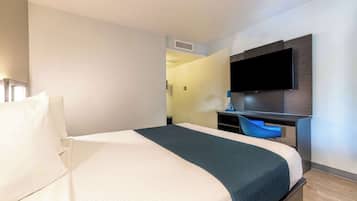 Ein Hotelzimmer mit einem Bett, einem Schreibtisch und einem an der Wand befestigten Flachbildfernseher.